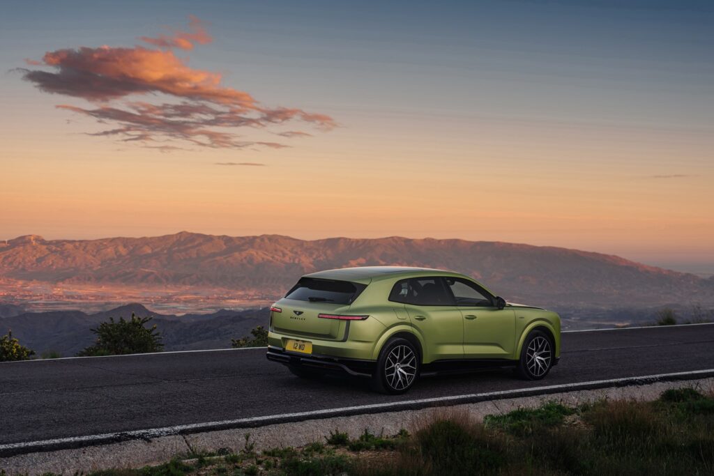 Rear three-quarter view of the Bentley Torcal overlooking a mountain valley at sunset