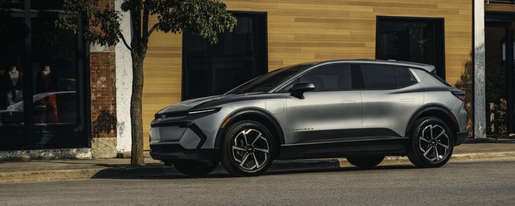 Silver 2026 Chevrolet Equinox EV parked on a city street, front three-quarter view