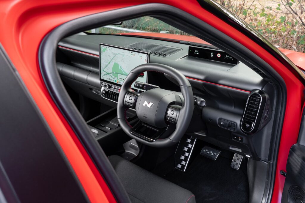 Hyundai IONIQ 3 interior with steering wheel and wide dashboard display, seen through the open driver door