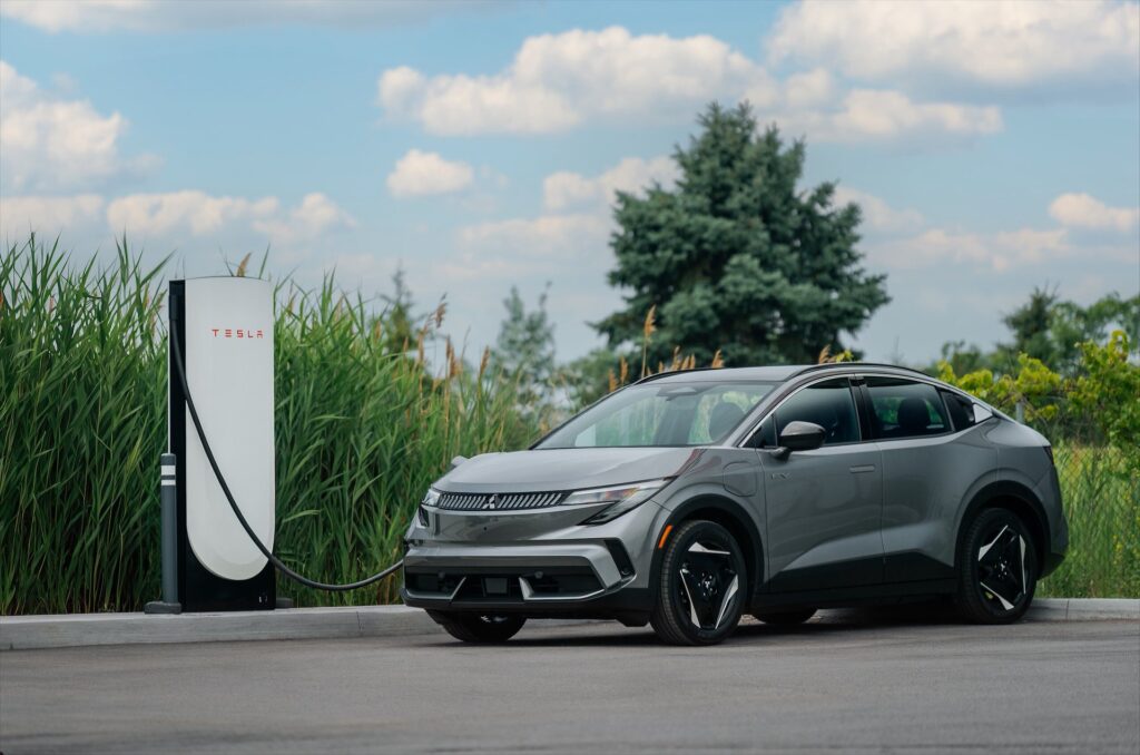 Gray 2027 Mitsubishi Eclipse Sportback EV parked beside a DC fast charger