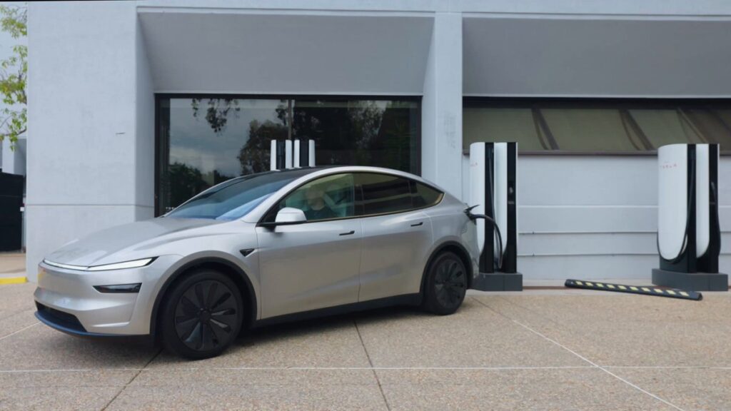Silver Tesla Model Y plugged into a Tesla Supercharger