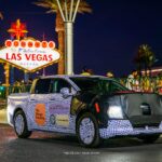 Camouflaged preproduction Ford Fathom electric pickup in front of the Welcome to Las Vegas sign at night
