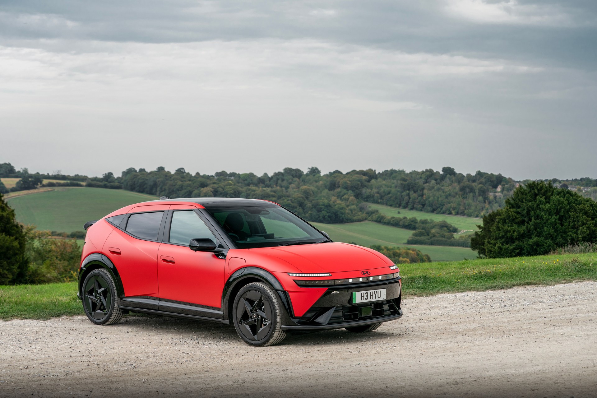 Matte red Hyundai IONIQ 3 N Line hatchback with UK plate H3 HYU on a rural hillside road