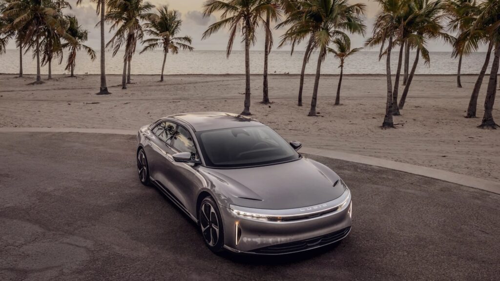 Lucid Air sedan parked by a palm-lined beach