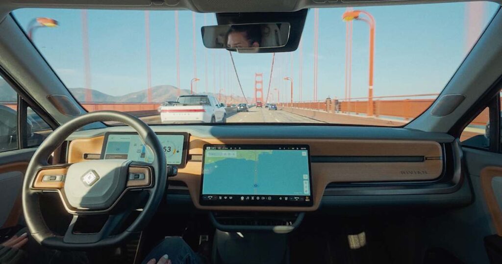 A Rivian R1 crossing the Golden Gate Bridge with the driver's hands off the wheel