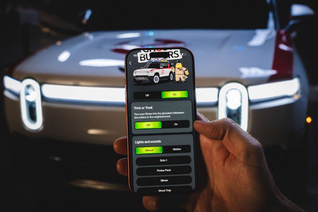 Rivian phone app showing Ghostbusters Trick or Treat controls in front of a white Ecto-R1