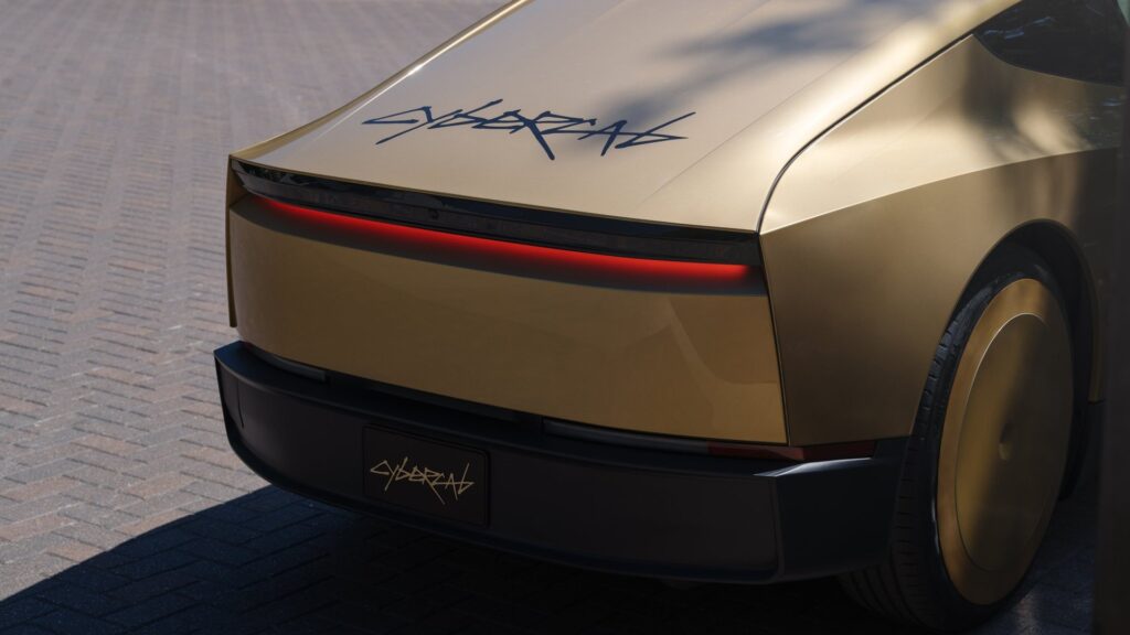 Close-up of the gold Tesla Cybercab rear with a full-width red light bar and Cybercab script lettering