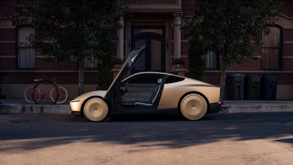 Gold Tesla Cybercab in profile with its door raised showing the two seats inside