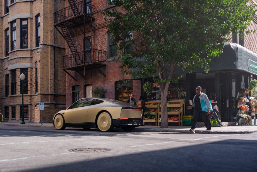 Gold Tesla Cybercab parked at a sunny street corner beside a flower and produce market
