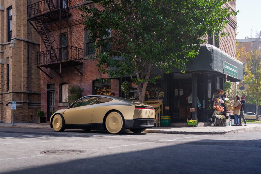 Gold Tesla Cybercab from the rear parked at a sunny city corner by a market