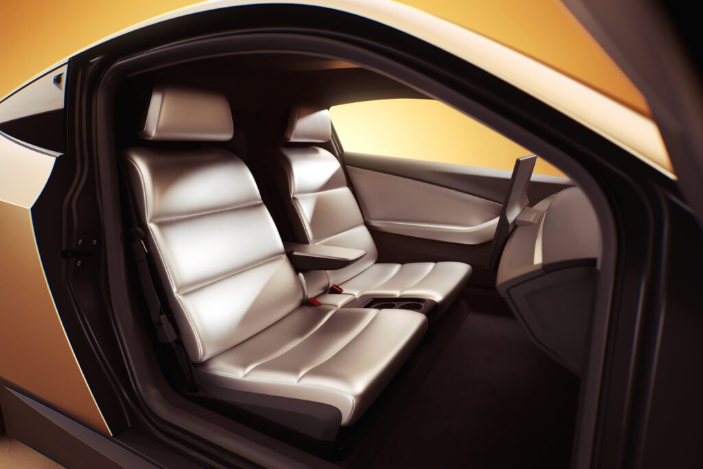 Interior of the Tesla Cybercab through the open door showing two light seats and no steering wheel