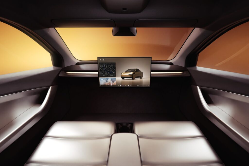 Tesla Cybercab cabin viewed from behind the seats showing the center screen and wide windshield