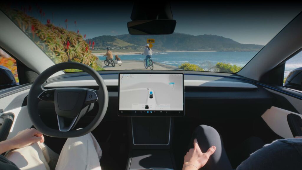 Driver's view inside a Tesla Model 3 as FSD (Supervised) drives along a coastal road past cyclists