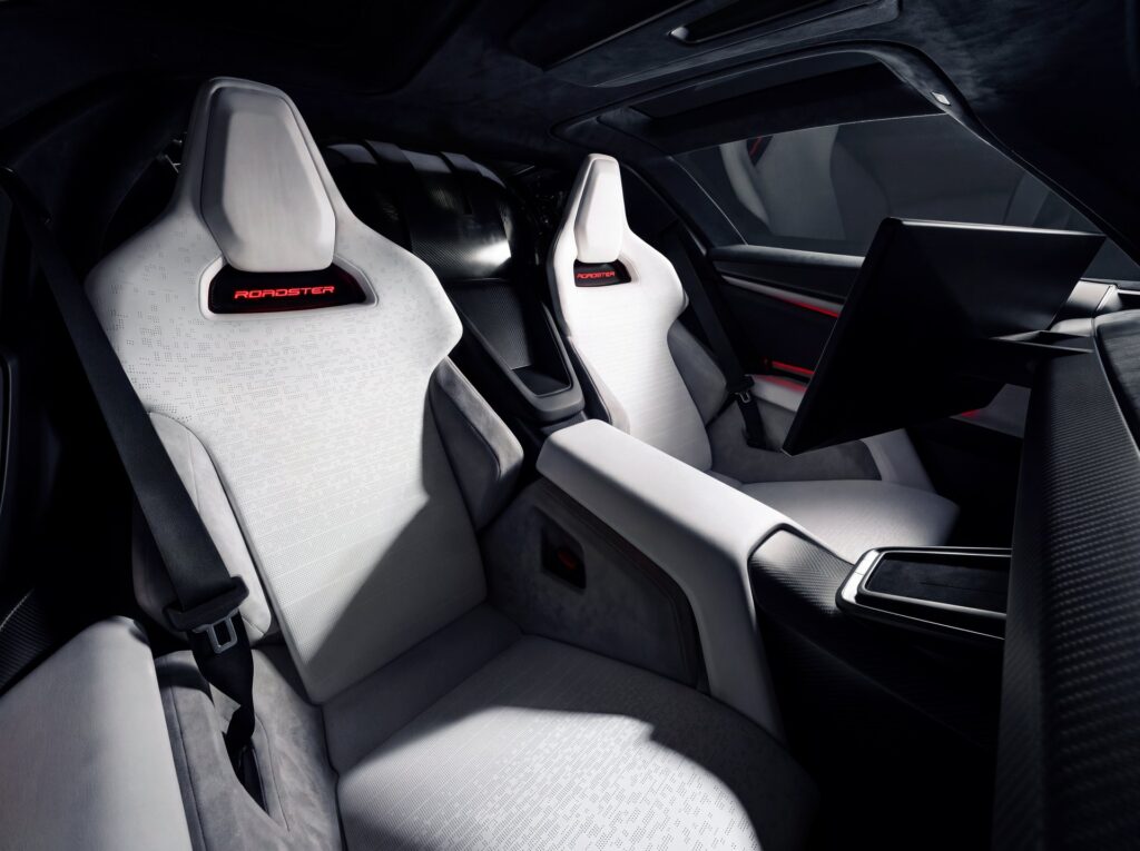 Tesla Roadster cabin with white sport seats, red ROADSTER logos and a floating center display