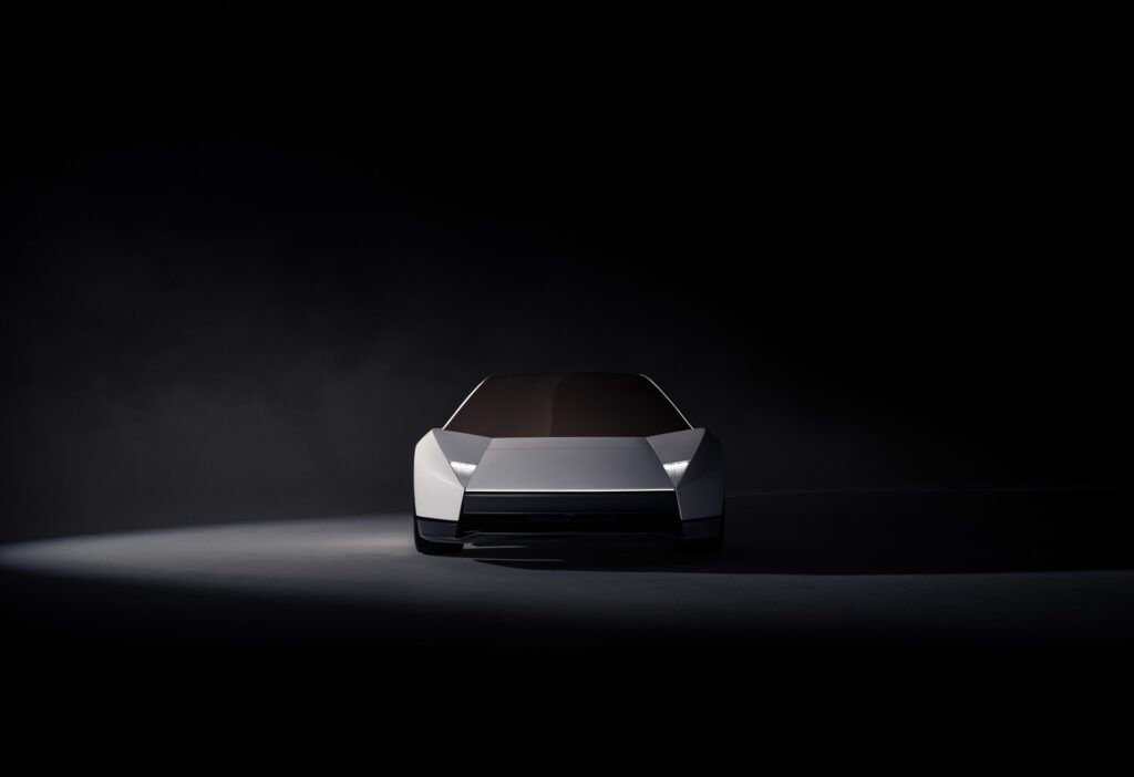 Front view of a white Tesla Roadster under a spotlight on a dark stage