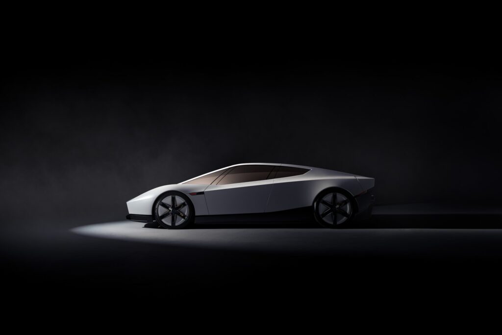 Side profile of a white Tesla Roadster with a low fastback roofline under a spotlight