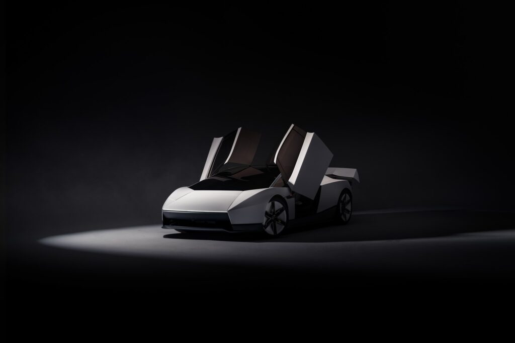 Front three-quarter view of a white Tesla Roadster with both doors raised and its wing deployed
