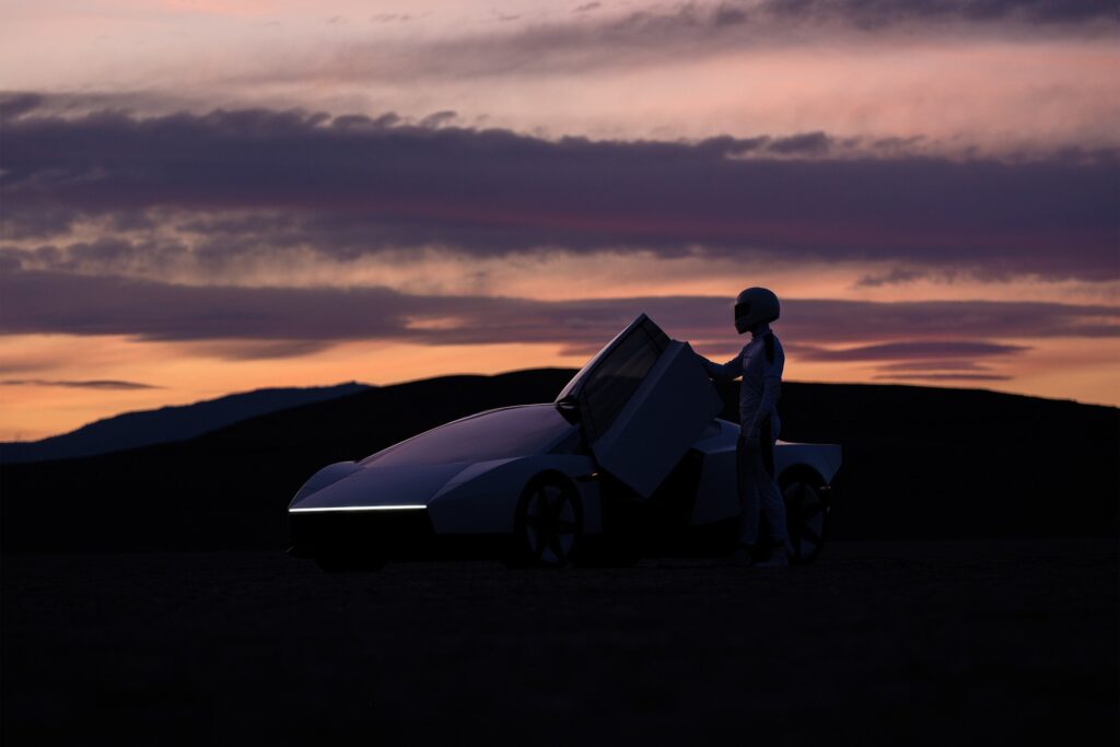 Silhouette of a Tesla Roadster with its door raised and a driver standing beside it at sunset