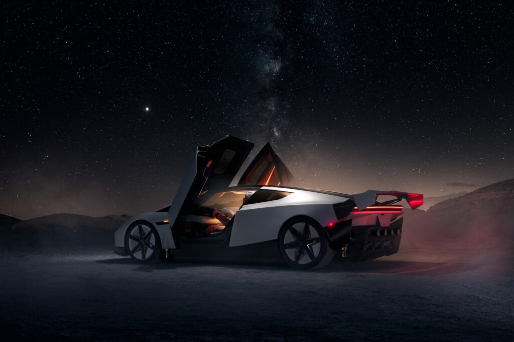 Tesla Roadster at night with its door open and wing up, lit under a starry desert sky