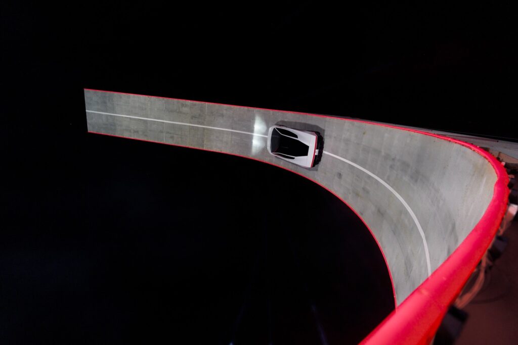 Overhead view of the white Tesla Roadster driving along the curved, red-edged ramp at the reveal