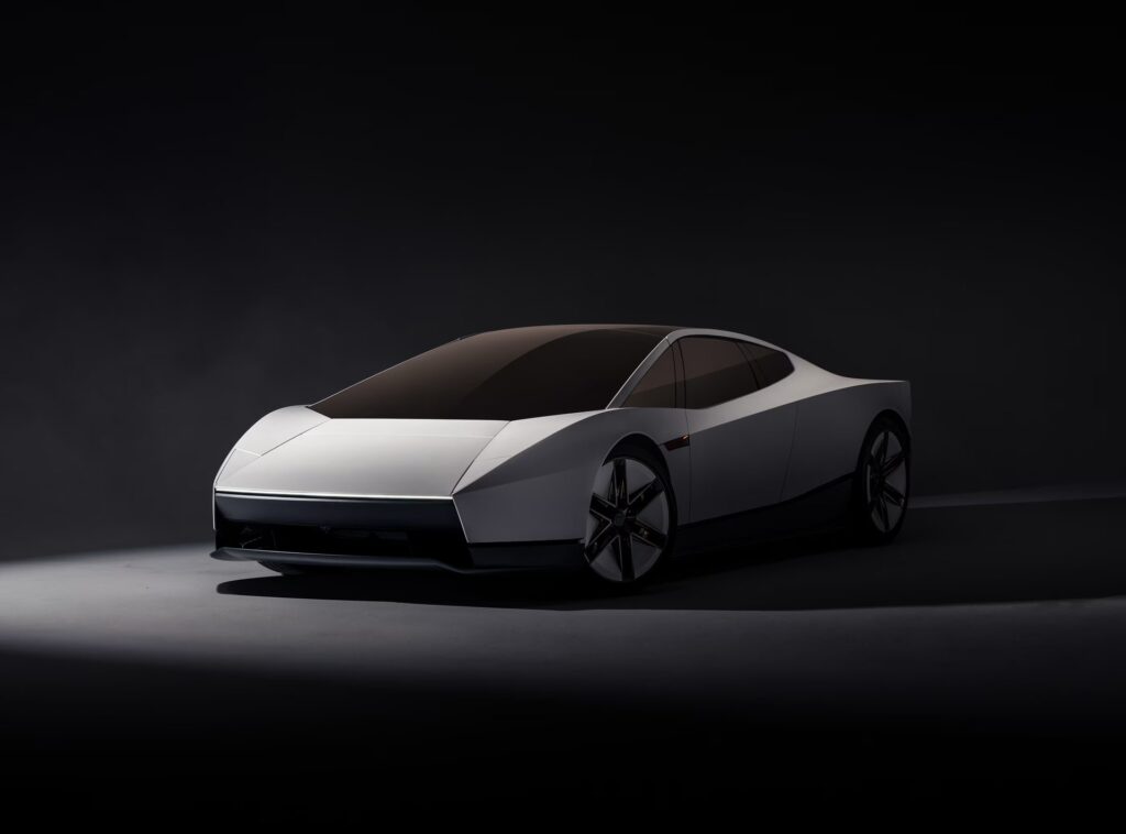 White Tesla Roadster in a dark studio, front three-quarter view showing the full-width light bar and tinted glass roof