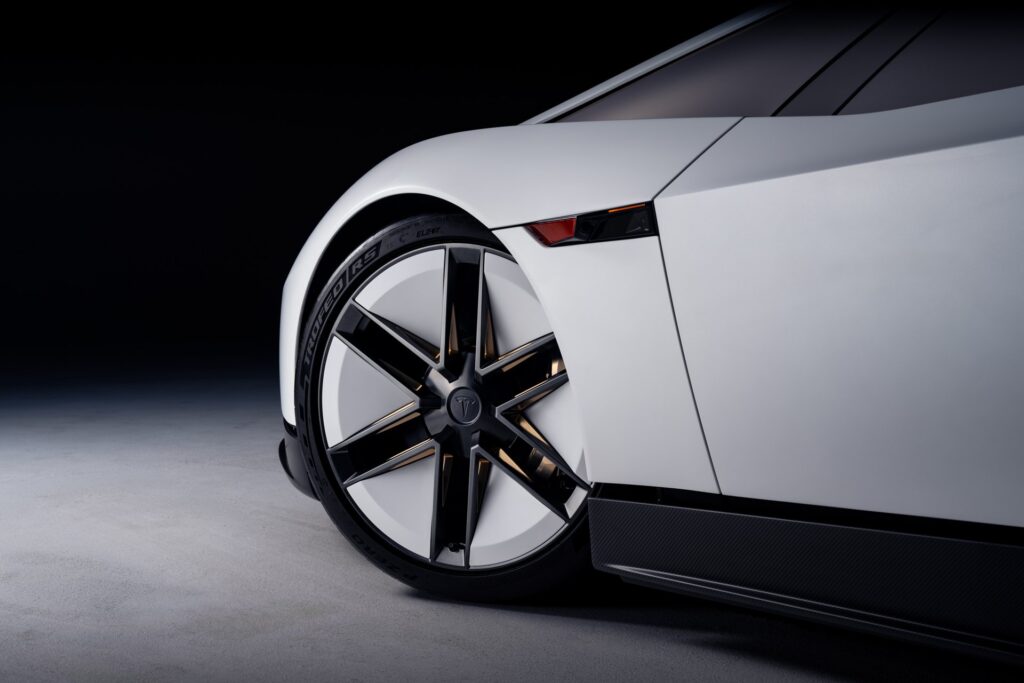 Close view of the Tesla Roadster's thin-spoke front wheel, carbon sill and tinted side glass